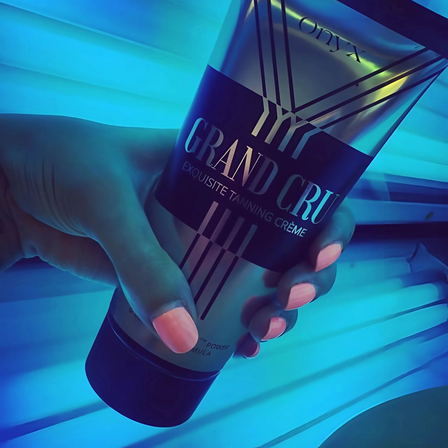 Nahaufnahme der Hand mit Onyx Grand Cru Bräunungslotion vor blauen UV-Lampen im Solarium – intensive Bräunungsformel