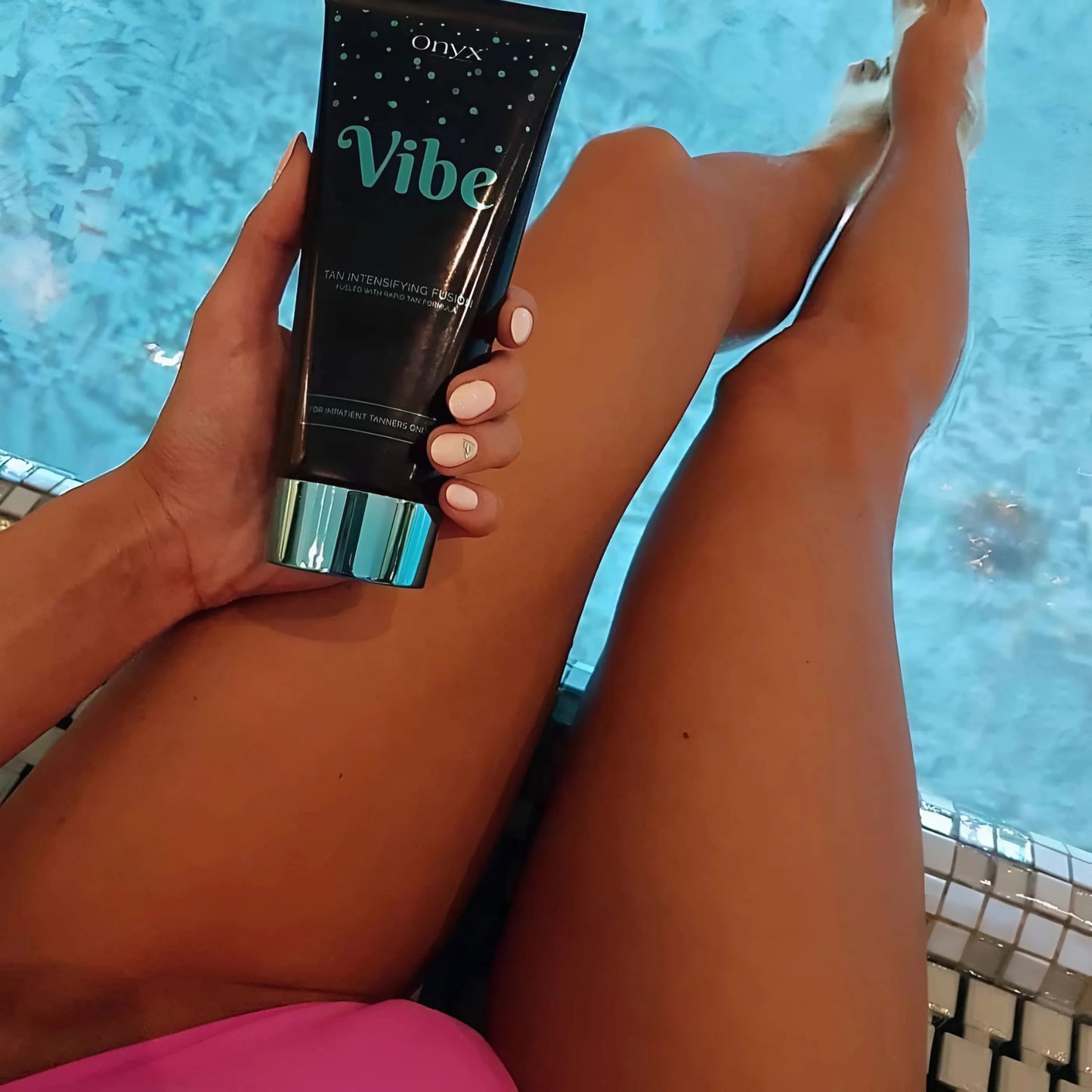 Beine am Poolrand mit Onyx Vibe Bräunungslotion in der Hand – entspannte Atmosphäre trifft auf intensive Bräunungspflege mit schneller Wirkung